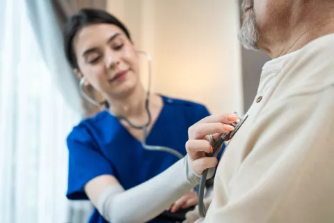 young woman nurse checking patient heartbeat