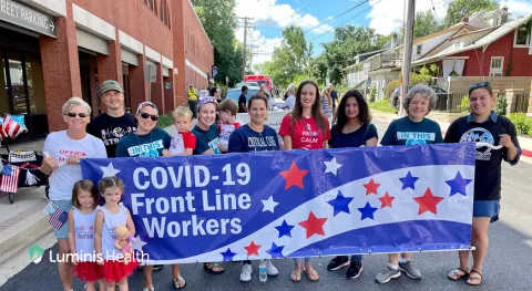 Healthcare workers standing behind banner that says COVID-19 Front Line Workers