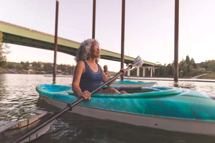 An older couple enjoy a late evening of kayaking on the river.