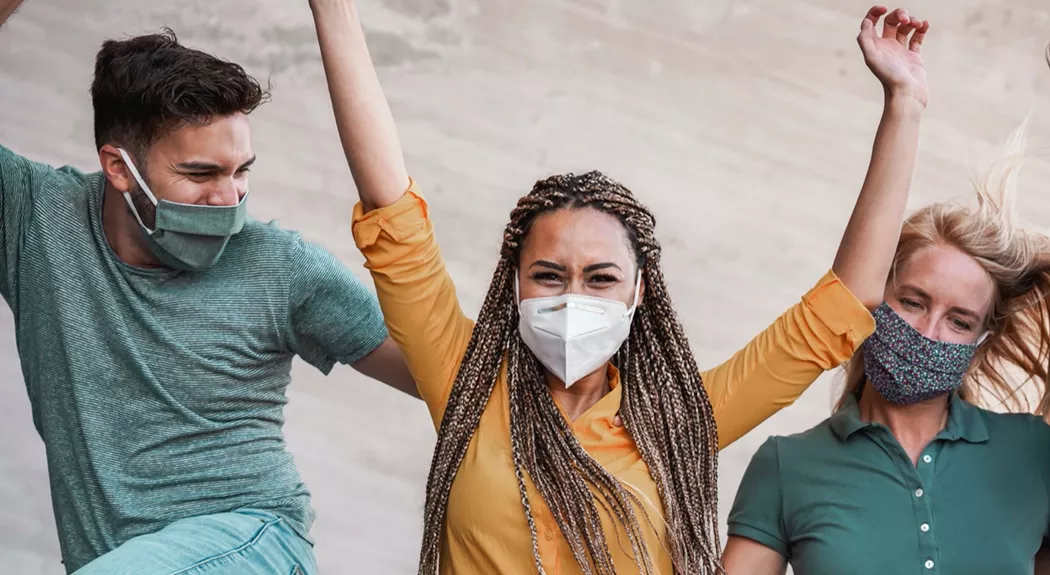 Three people celebrating while wearing masks