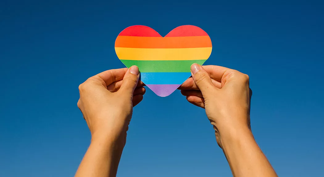 hands holding up rainbow heart