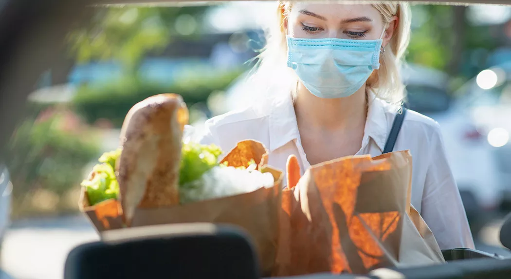 woman wearing mask unloading groceries