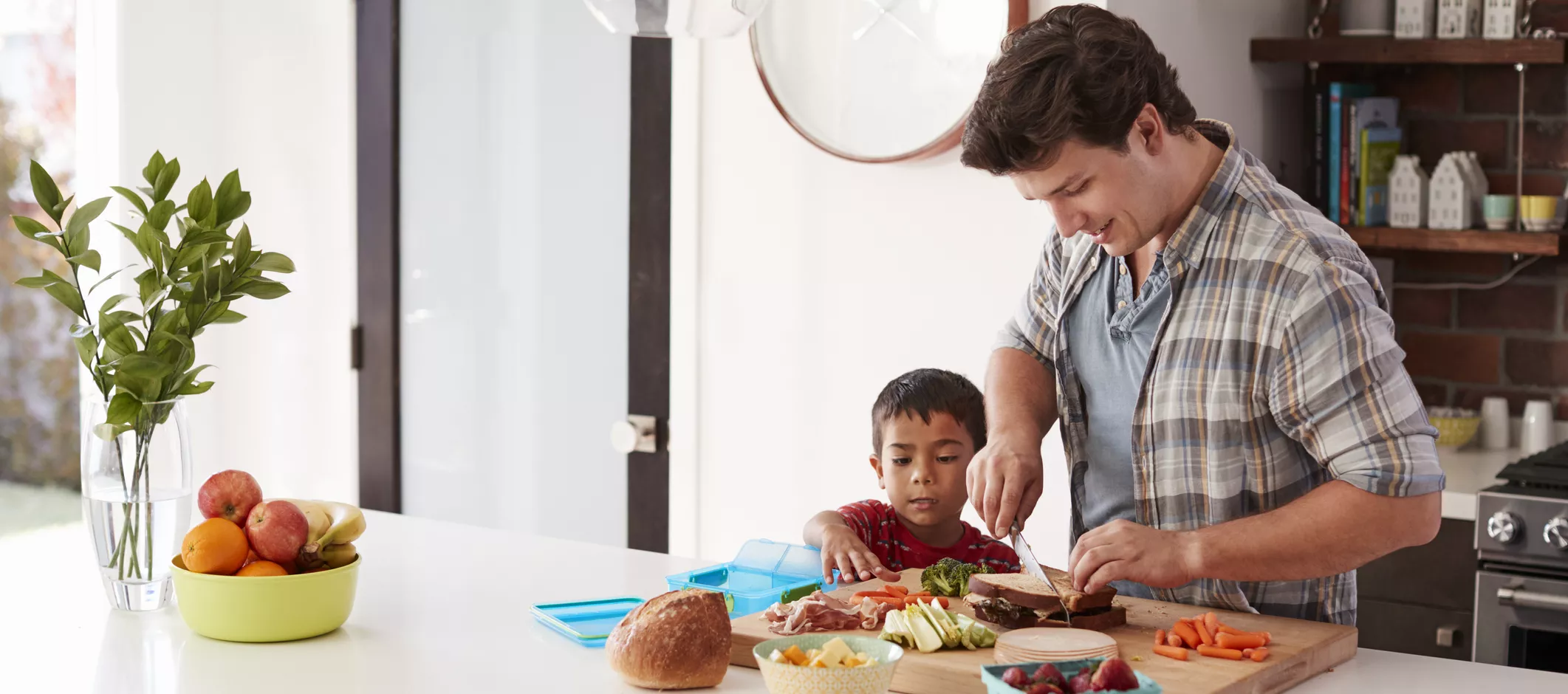 Father And Son Making School Lunch In Kitchen At Home