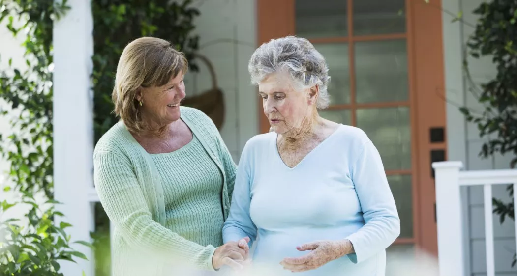 Elderly woman walking with adult daughter