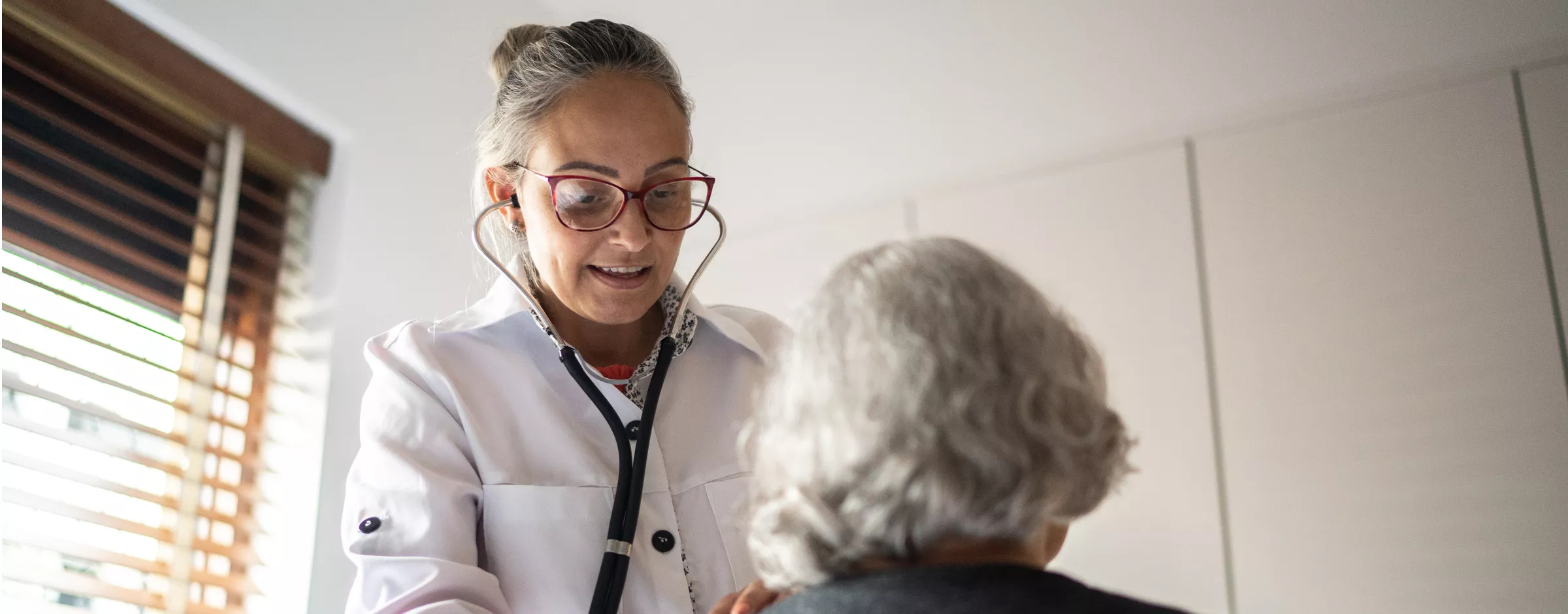 Doctor using stethoscope to exam senior woman