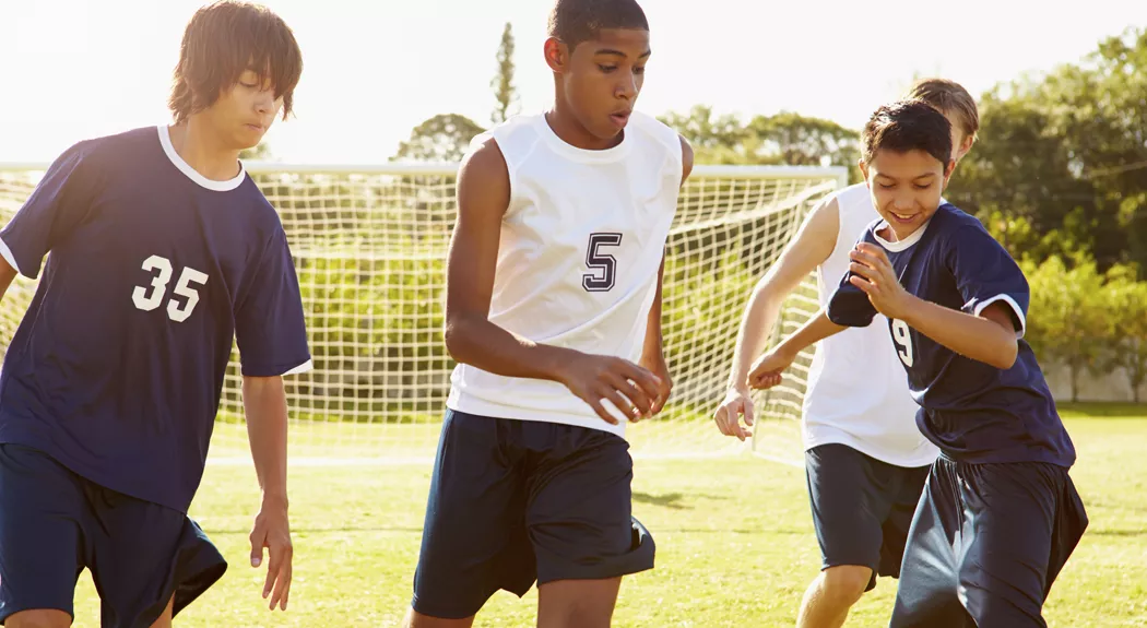 Members Of Male High School Soccer Playing Match